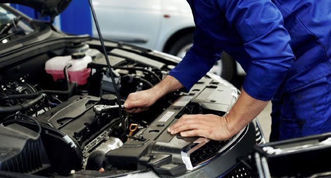 Technician servicing an open car engine